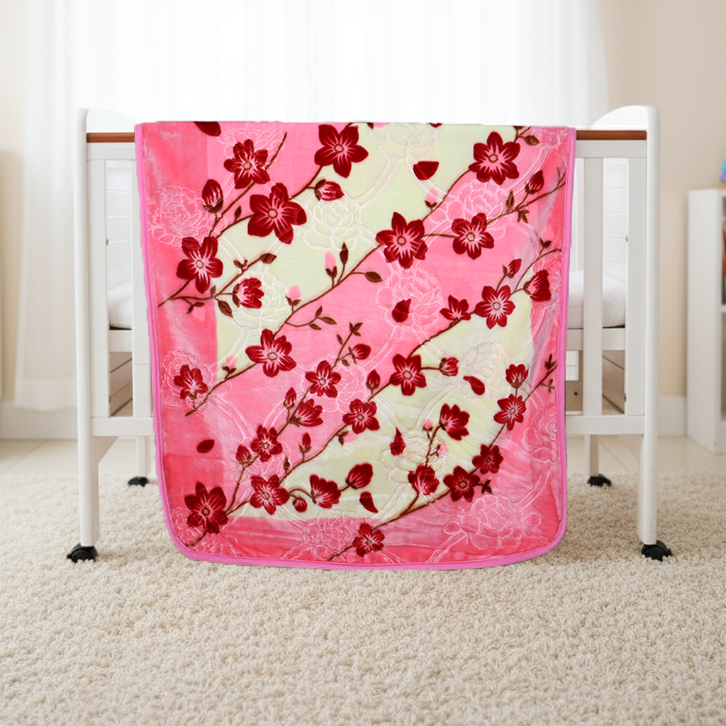Pink floral blanket draped over a crib in a room.