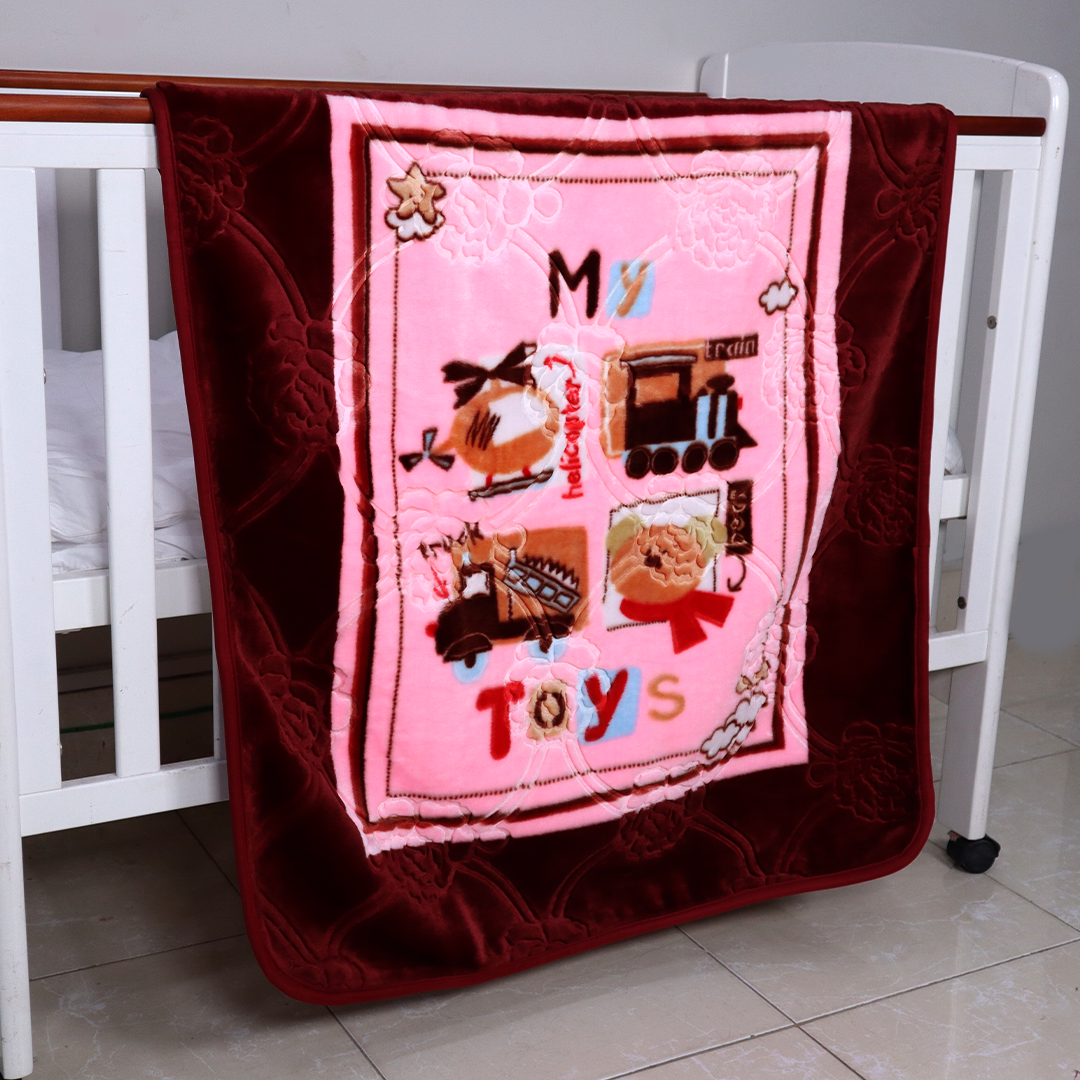 Pink quilt with toy-themed design draped over a crib
