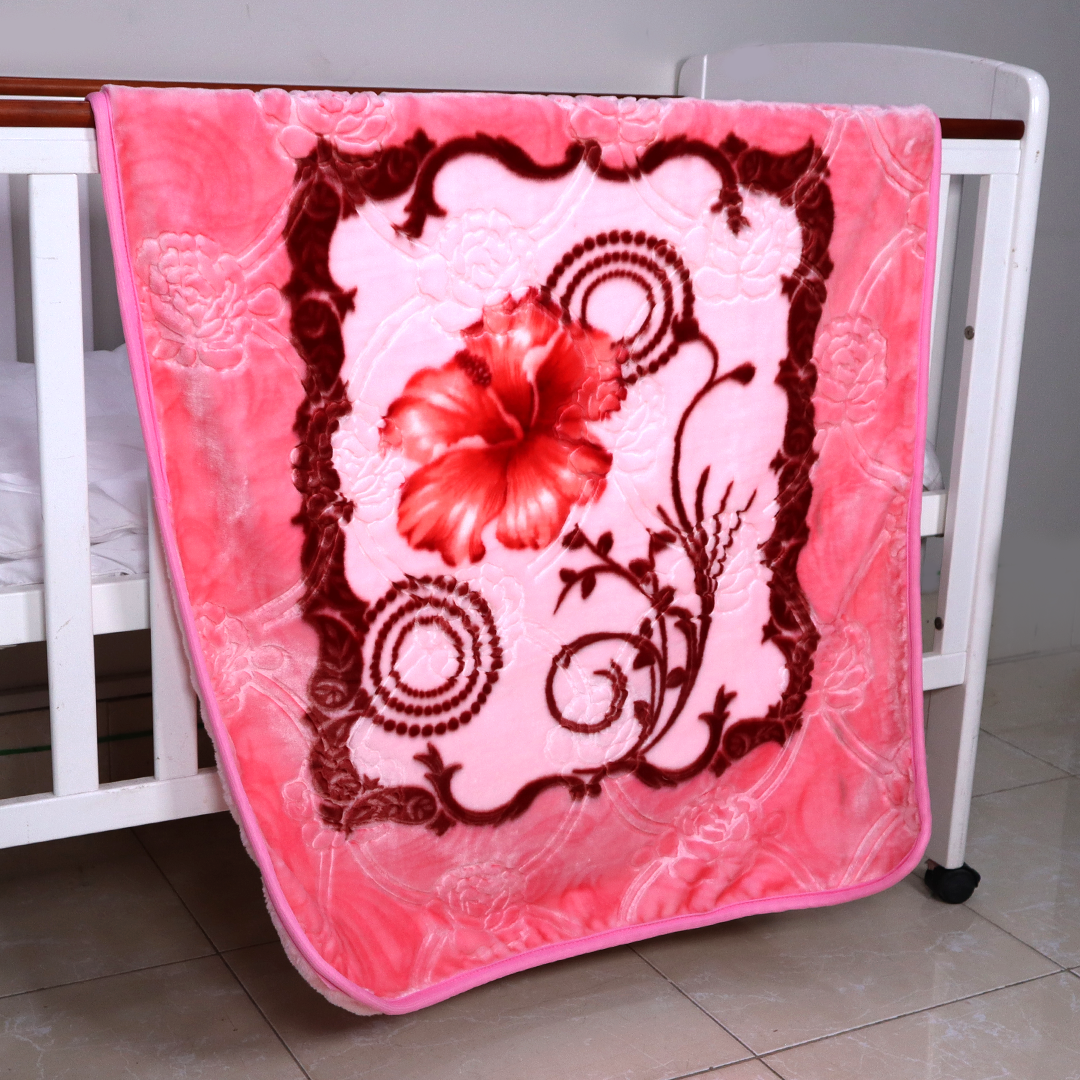 Pink floral blanket with red flower design draped over a crib.