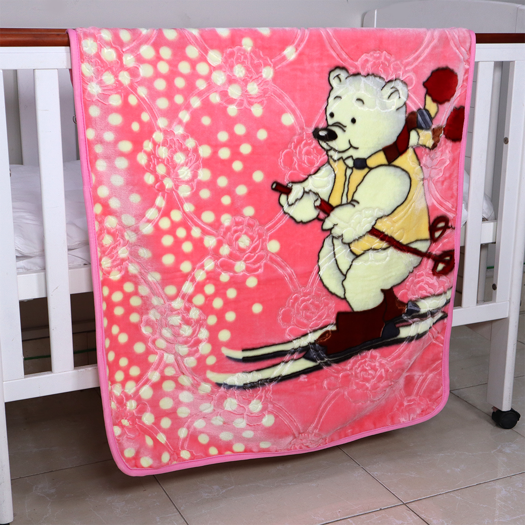Pink blanket with a cartoon bear skiing design on a crib.