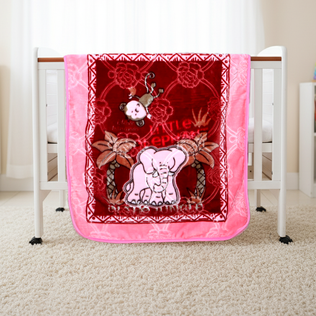 Pink and red baby blanket with elephant design on a crib