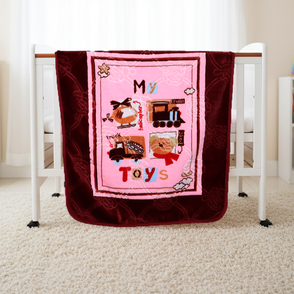 Pink and red quilt with toy-themed design on a crib