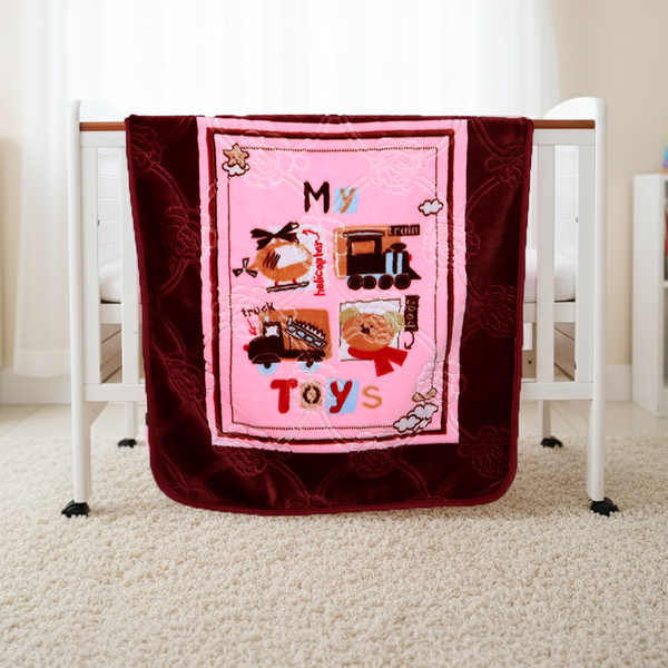 Pink and red quilt with toy-themed design on a crib