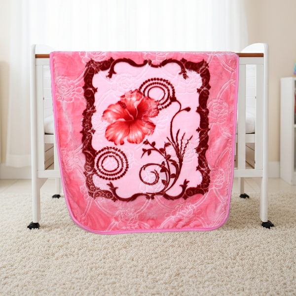 Pink floral blanket draped over a white crib with a red flower design.