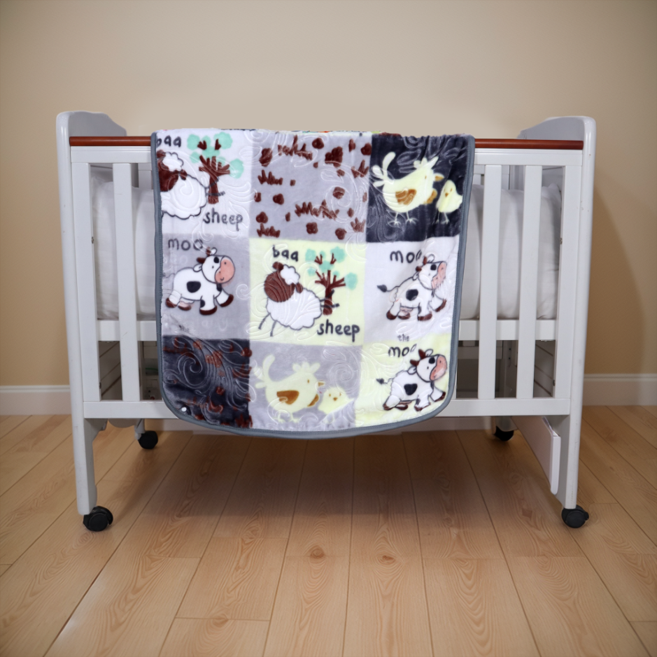Patchwork quilt with farm animal patterns draped over a crib on a wooden floor.