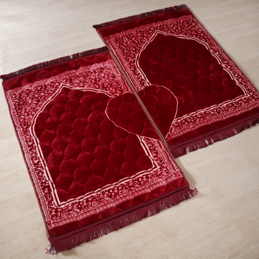 Two red prayer mats with intricate patterns on a light beige floor.