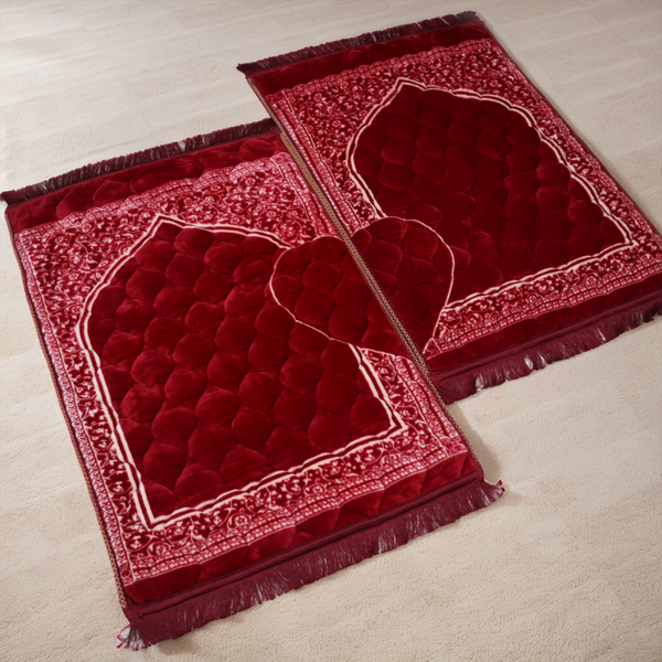 Two red prayer mats with intricate patterns on a light beige floor.