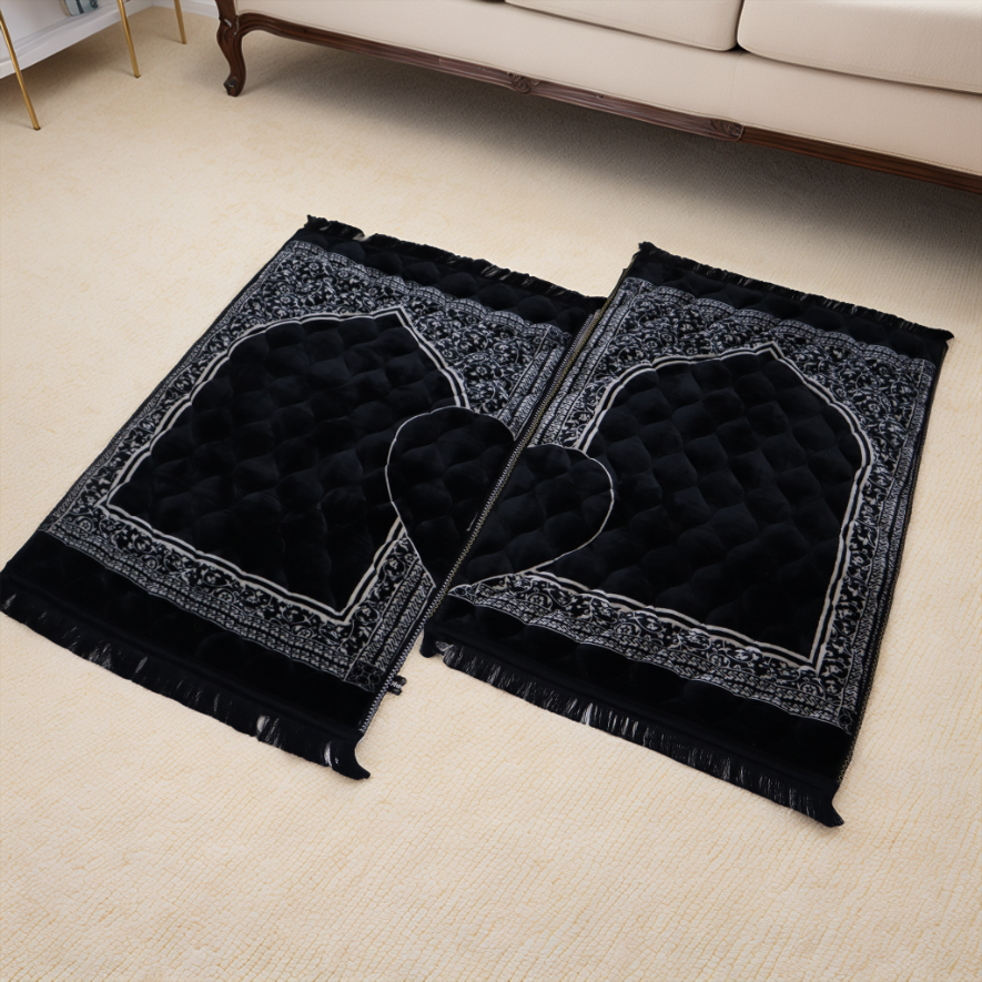 Two black prayer mats with decorative patterns on a beige carpet.