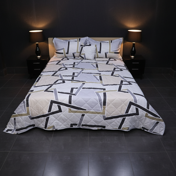 Geometric patterned quilt on a bed in a dimly lit bedroom