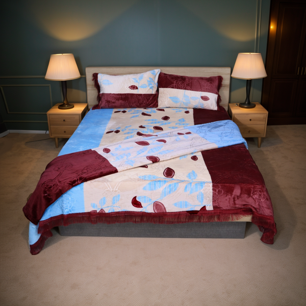 Bedroom with a bed covered in a red and blue patterned comforter, flanked by two lamps on nightstands.