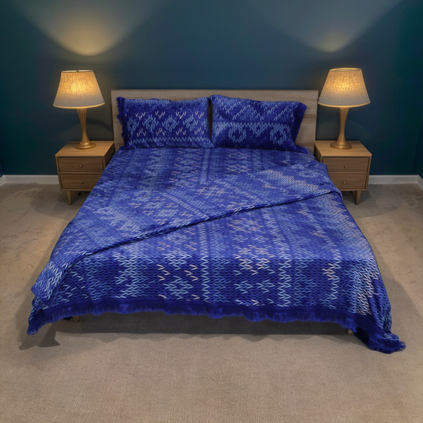 Bedroom with a bed covered in blue patterned bedding, two nightstands with lamps, and a dark blue wall.