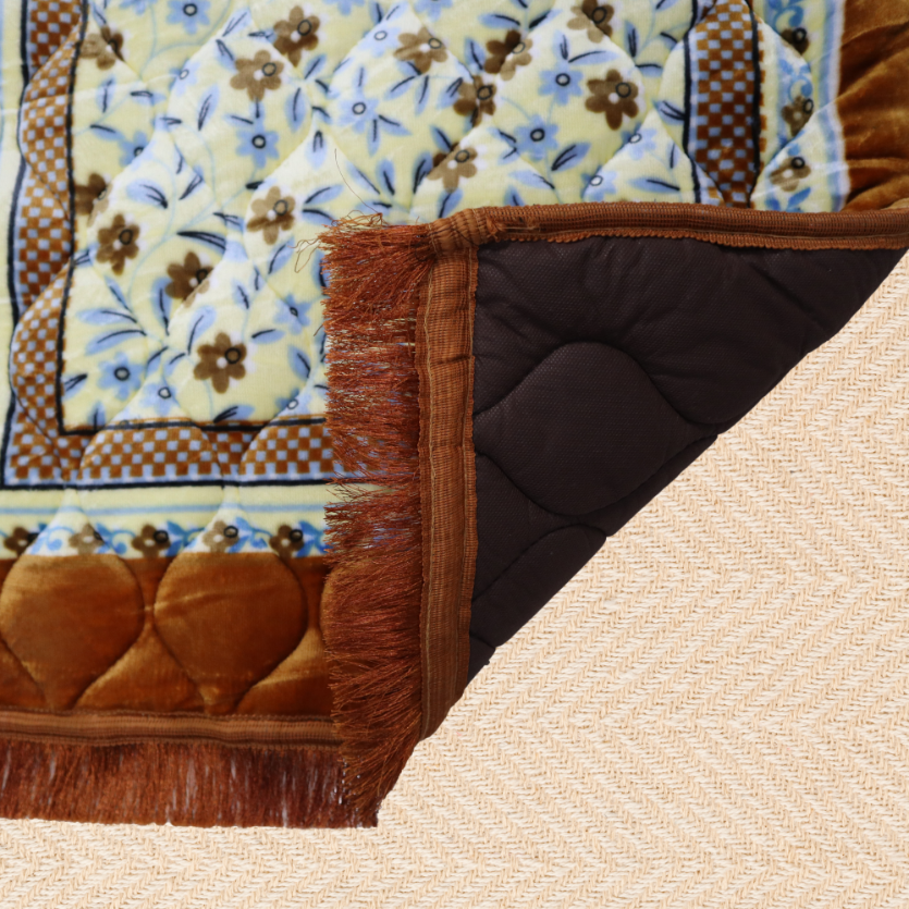 Close-up of a prayer mat with floral patterns and brown border on a beige surface.