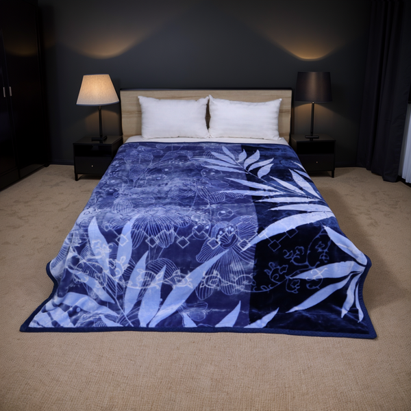 Bed with a blue and white patterned comforter in a dimly lit bedroom.