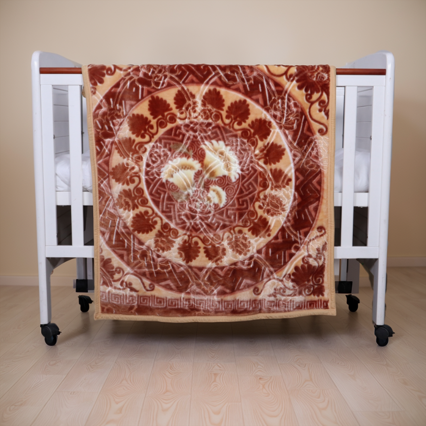 Decorative blanket with floral pattern draped over a crib on a wooden floor.
