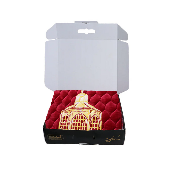 Decorative item on red fabric in a white box with visible branding.